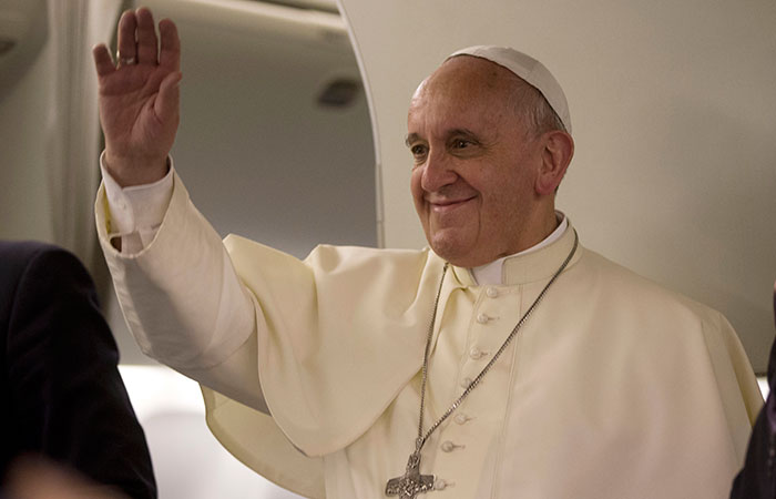 Pope Francis waves to journalists as he arrives for a press conference he held aboard the papal flight on his way back to Rome at the end of a three day trip to the Midle East, Monday, May 26, 2014 (AP Photo/Andrew Medichini, Pool)