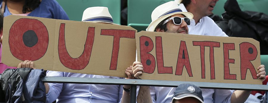 Two spectators hold signs reading Out Blatter, referring to newly re-elected FIFA president Sepp Blatter during the quarterfinal match of the French Open tennis tournament between Spains Garbine Muguruza and Lucie Safarova of the Czech Republic at the Roland Garros stadium, in Paris, France, Tuesday, June 2, 2015. Blatter said Tuesday he will resign from his position amid corruption scandal. (AP Photo/David Vincent)