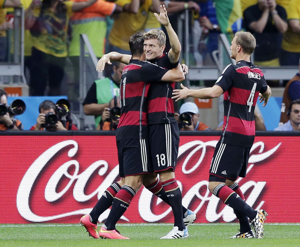 In this July 8, 2014 photo, Germany's Toni Kroos, centre, celebrates after scoring his side's third goal during the World Cup semifinal soccer match between Brazil and Germany near a Coca-Cola advertisement at the Mineirao Stadium in Belo Horizonte, Brazil. With billions of dollars at stake and few other ways to tap into the global love of soccer, FIFA sponsors like Adidas, Coke and McDonald’s are in the tricky position of wanting to preserve their investment while avoiding being tainted by the corruption scandal that’s threatening soccer’s global governing body. (AP Photo/Matthias Schrader, File)