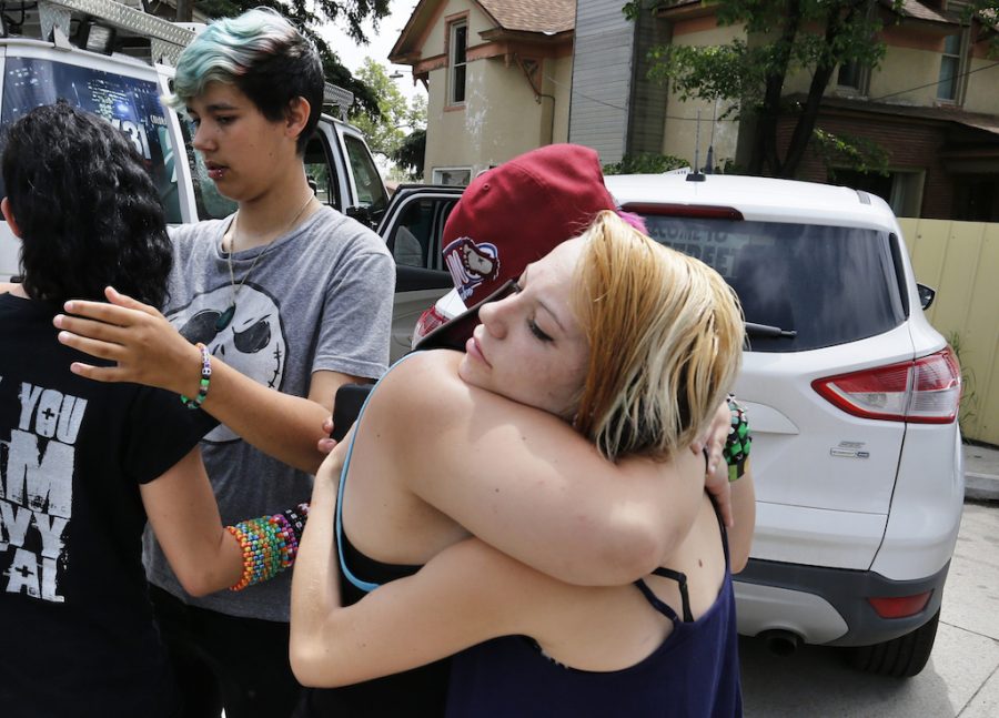 Ciera Rogers, far right, receives condolences from her friend Sam Hinde, on the loss of Rogers grandfather, who was shot and killed the night before on a sidewalk near his home, in the northern Colorado town of Loveland, Thursday, June 4, 2015. At left, facing, Emmett Pelissier hugs Ciera Rogers sister Sadie. (AP Photo/Brennan Linsley)
