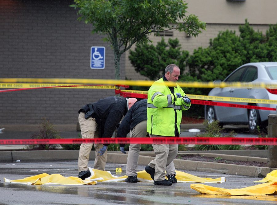 Boston police officers and detectives investigate at the scene of a shooting Tuesday morning, June 2, 2015) at 4600 Washington St. in Roslindale, Mass. A man under surveillance by terrorism investigators has been shot and killed by a Boston police officer. Police Commissioner William Evans confirmed from the scene that the man shot at about 7 a.m. at a pharmacy in the citys Roslindale neighborhood has died. Evans said the man was under surveillance by the Joint Terrorism task Force.  (Mark Garfinkel/The Boston Herald via AP) 