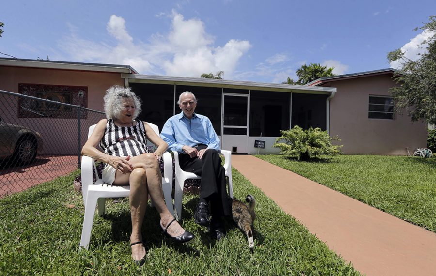 In this May 11, 2015 photo, Al Karp, right, and wife Saundra, pose in front of their home in North Miami Beach, Fla. The Karps, along with their son, Larry, perform old standards locally as the Karp Family band to ease stress and help raise money to save their home from foreclosure. (AP Photo/Alan Diaz)