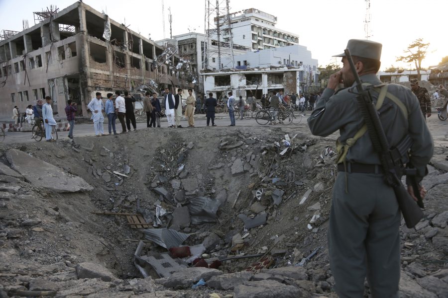 Security forces stand next to a crater created by massive explosion in front of the German Embassy in Kabul, Afghanistan, Wednesday, May 31, 2017. The suicide truck bomb hit a highly secure diplomatic area of Kabul killing scores of people and wounding hundreds more. (AP Photo/Rahmat Gul)
