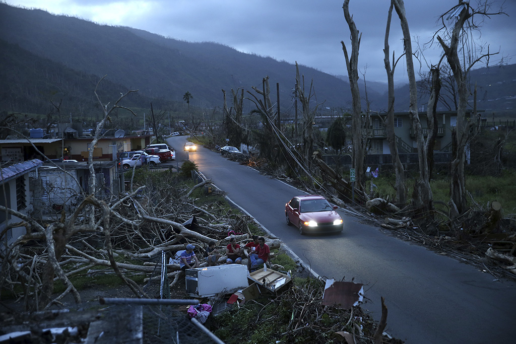 Neighbors sit on a couch outside their destroyed homes as sun sets in the aftermath of Hurricane Maria, in Yabucoa, Puerto Rico.