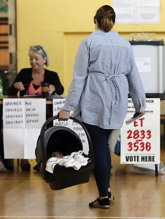 A woman carries a baby in a cot as goes to cast her vote at a polling station in the referendum on the 8th Amendment of the Irish Constitution, in Dublin, Friday, May 25, 2018. Voters throughout Ireland have begun casting votes in a referendum that may lead to a loosening of the country's strict ban on most abortions. (Niall Carson/PA via AP)