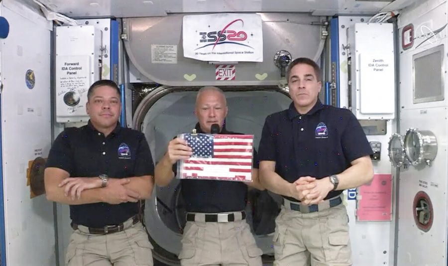 Astronauts in the space station hold a small American flag