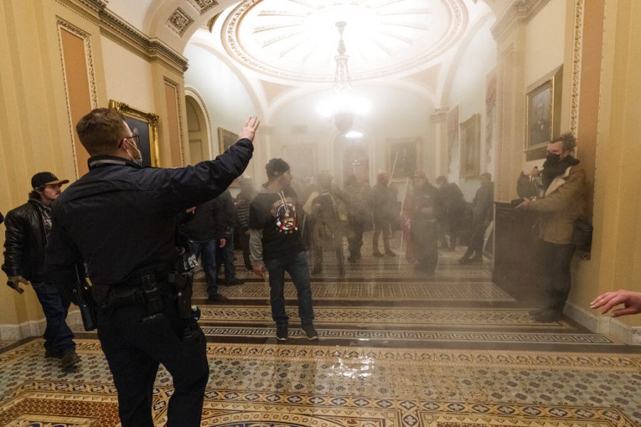 FILE - In this Jan. 6, 2021, file photo, smoke fills the walkway outside the Senate Chamber as rioters are confronted by U.S. Capitol Police officers inside the Capitol in Washington. Outside pressures and internal strife are roiling two far-right extremist groups after members were charged in the attack on the U.S. Capitol. Former President Donald Trump’s lies about a stolen 2020 election united an array of right-wing supporters, conspiracy theorists and militants on Jan. 6. (AP Photo/Manuel Balce Ceneta, File)