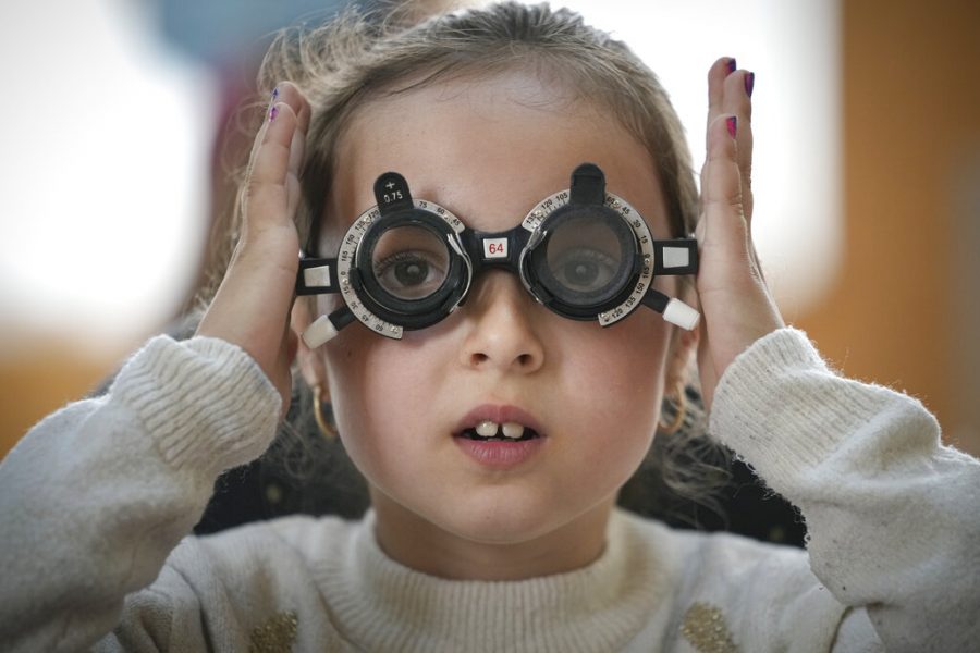 Girl adjusts glasses during eyesight examination