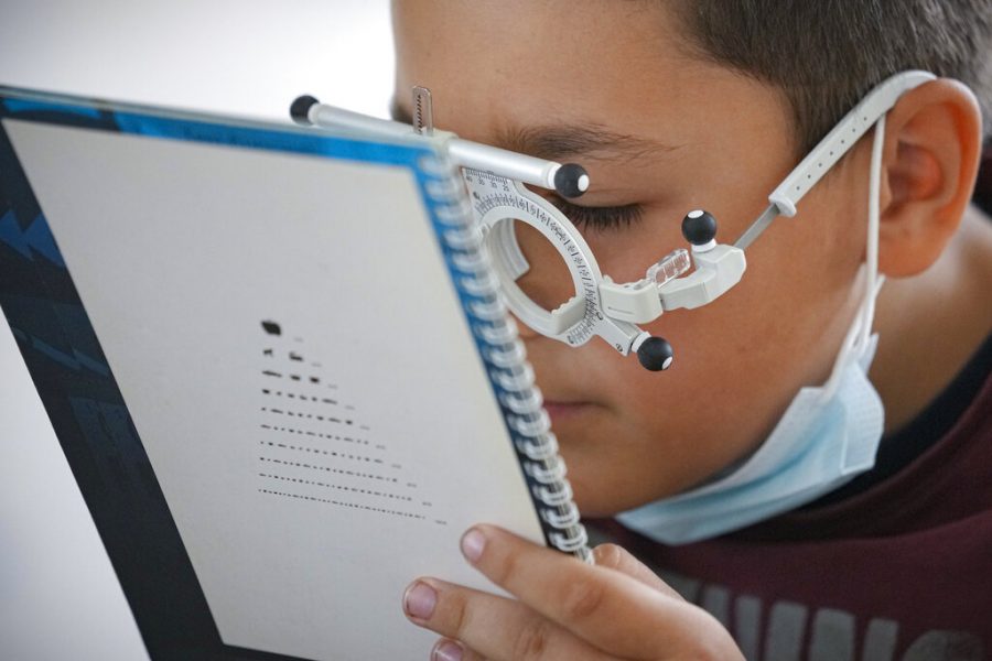 A boy looks at sample text during an eye examination