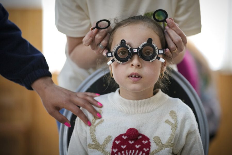 A woman holds her hand on her daughter during an eyesight examination performed by volunteer ophthalmologists working with the humanitarian organization Casa Buna, or Good House, in Nucsoara, Romania, Saturday, May 29, 2021. Dozens of disadvantaged young Romanian children got a chance to get their eyesight examined for the first time in their lives at an event in a remote village in the countrys southern Carpathian Mountains.(AP Photo/Vadim Ghirda)