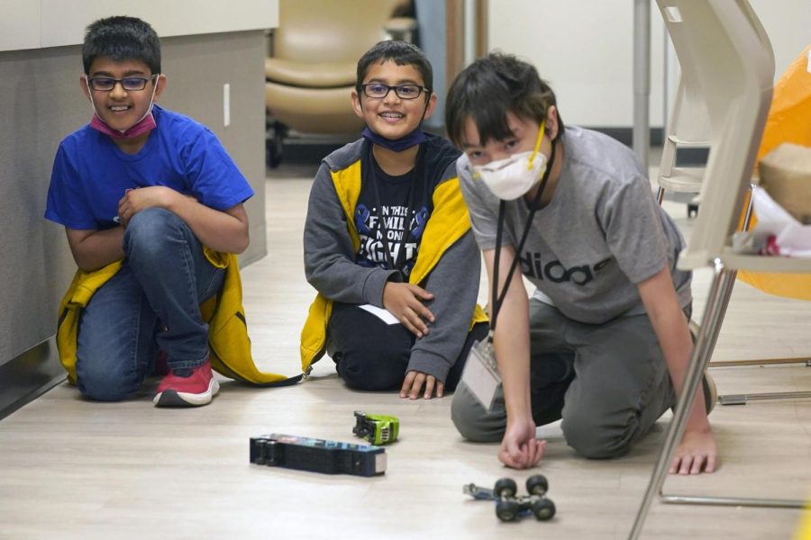 Ronan Kotiya and his brother Keaton Kotiya look on and smile after Alex Oliver pushed a toy car during a break in a workshop for young caregivers of ALS diagnosed family members in Dallas, Texas, April 9. 