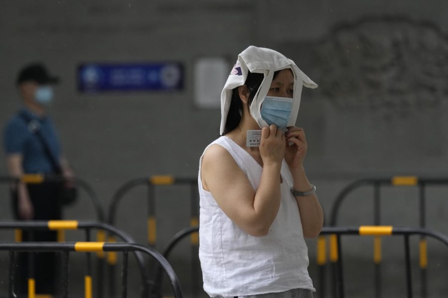 A resident covers her head as it starts to rain at a mass COVID test site, Sunday in Beijing.