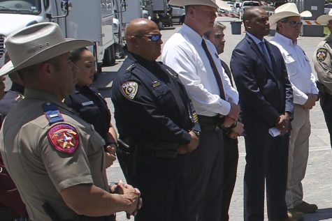 A group of people stand at an outdoor press conference, some in police uniforms.