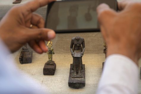 A reporter films a headless bronze statue of Imhotep