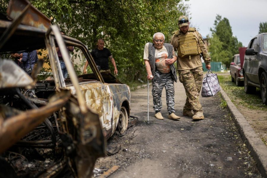 A volunteer helps a man leaving his home in a building damaged by an overnight missile strike, in Sloviansk, Ukraine on May 31, 2022. 