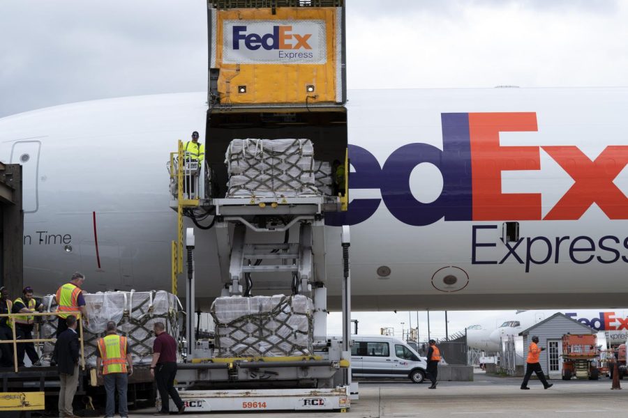 Workers unload a Fedex Express cargo plan carrying infant formula