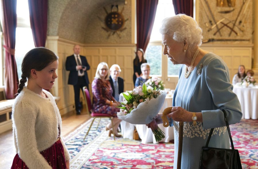 FILE - Britains Queen Elizabeth II receives a posy from Harriet Reeve, 9, during a reception to celebrate the start of the Platinum Jubilee, at Sandringham House, her Norfolk residence, in Sandringham, England, Saturday, Feb. 5, 2022. Britain is getting ready for a party featuring mounted troops, solemn prayers — and a pack of dancing mechanical corgis. The nation will celebrate Queen Elizabeth II’s 70 years on the throne this week with four days of pomp and pageantry in central London. (Joe Giddens/Pool Photo via AP, File)