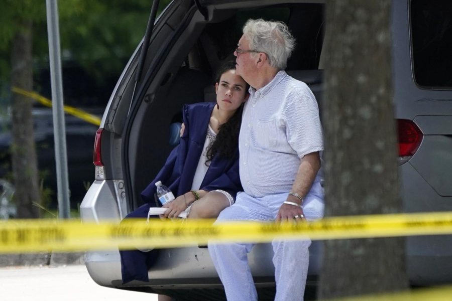 A man comforts a young woman wearing a graduation gown at the scene of a shooting at Xavier University in New Orleans on Tuesday,