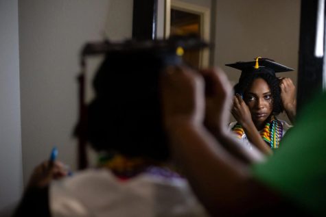 A person puts on a grad cap looking in the mirror