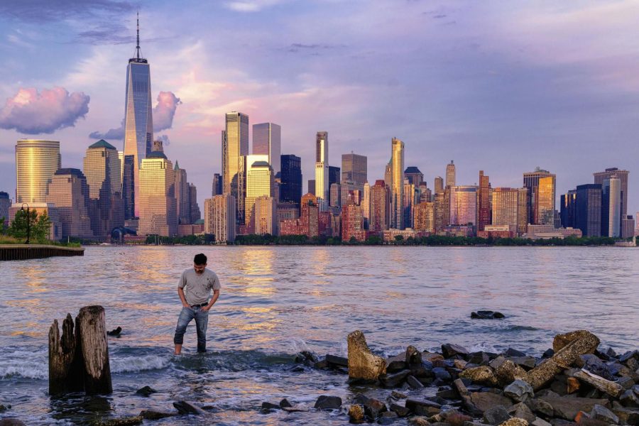 A man checks his footing as he wades through the Morris Canal Outlet in Jersey City, New Jersey, as the sun sets on the lower Manhattan skyline of New York City, May 31, 2022.