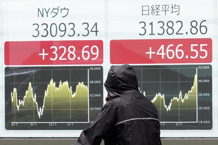 A person looks at an electronic stock board showing Japans Nikkei 225 and New York Dow indexes at a securities firm in the rain May 29, 2023, in Tokyo. Asian shares are mostly higher after President Joe Biden and House Speaker Kevin McCarthy reached a final agreement on a deal to raise the U.S. national debt ceiling.