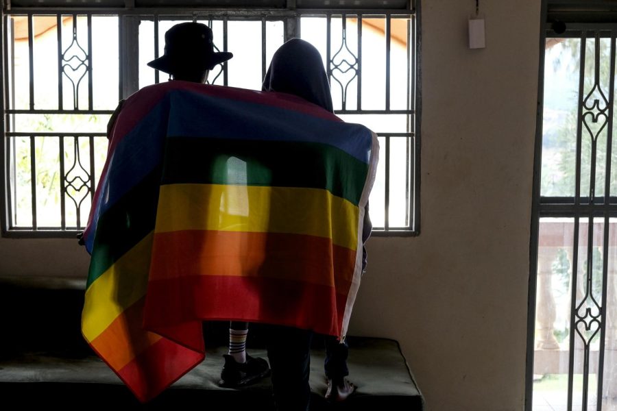 A gay Ugandan couple cover themselves with a pride flag.