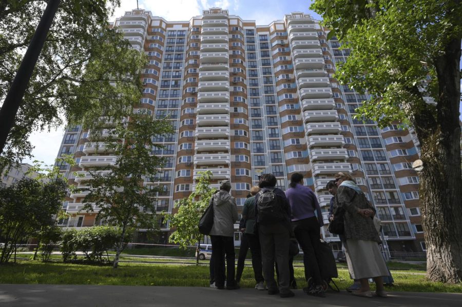 People look at a the apartment building in Moscow, Russia, after it was attacked by Ukrainian drones.